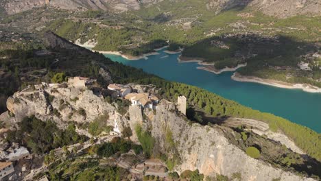 drone orbiting over the castle of guadalest and behind the blue lake