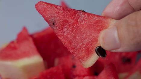 close-up of a hand holding a slice of watermelon