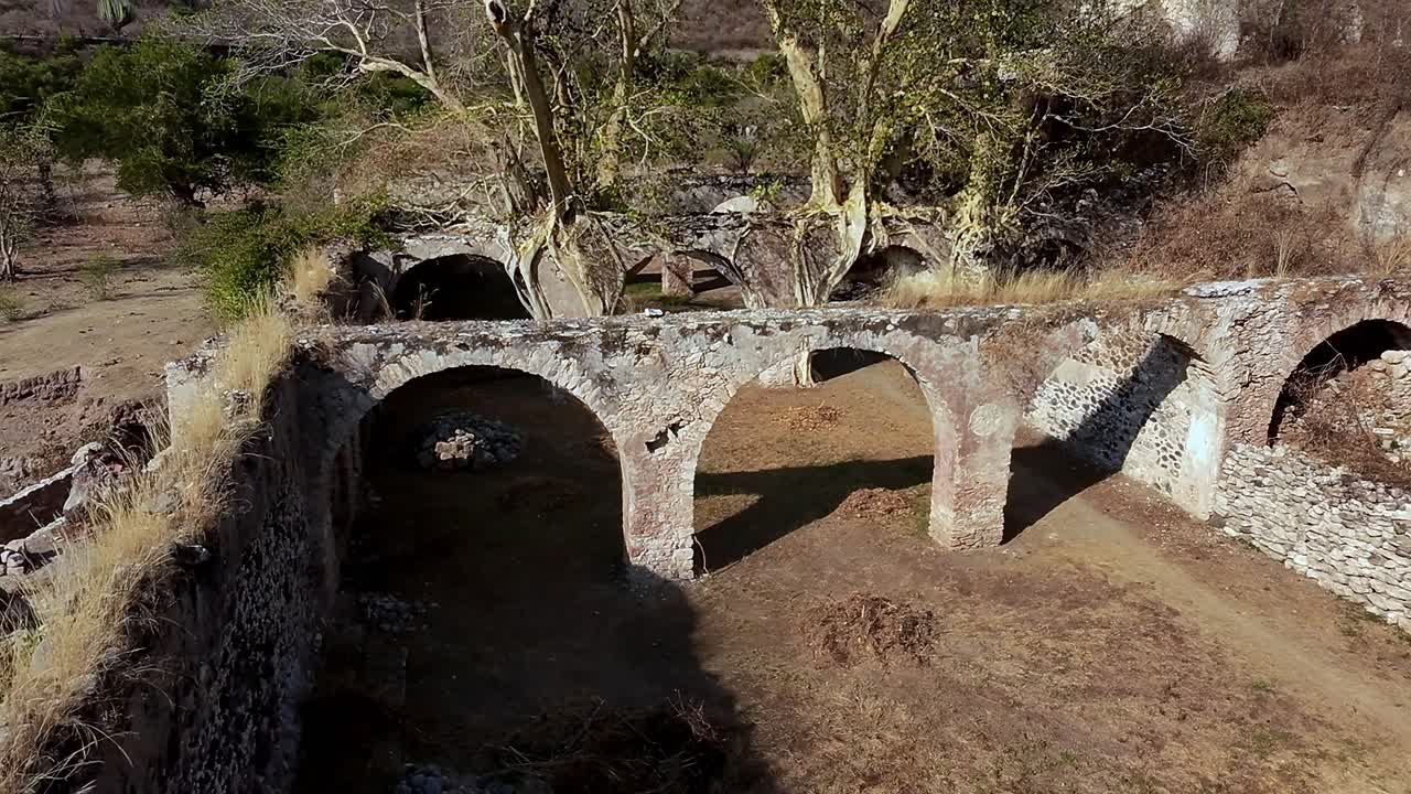 Aerial: Ex Hacienda de San Jacinto Ixtoluca, aqueducts with rocky wall during the day in La Mezquitera, Morelos, Mexico, crane down drone shot