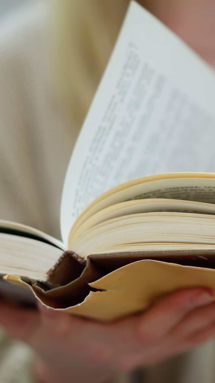 vista de cerca de la mano de la dama blanca girando a una nueva página, con pantalones de jean, con estructura moderna y flor decorativa verde borrosa en el fondo