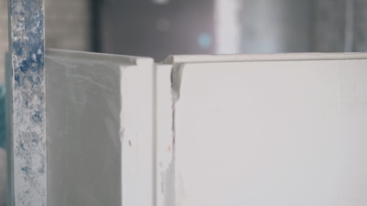 homem segura medidas de parede e bate placas de gesso