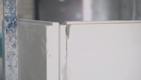 man holds wall measures and beats gypsum plasterboard