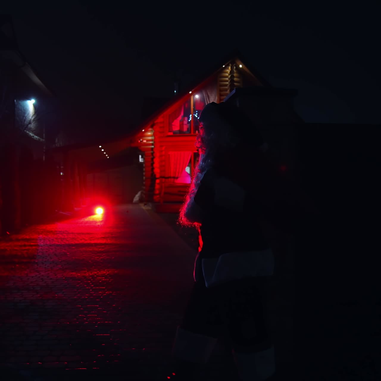 Santa Claus with bag walking on street at Christmas night. Silhouette of Santa carrying presents for children in winter at night. Christmas tree in window. Side view