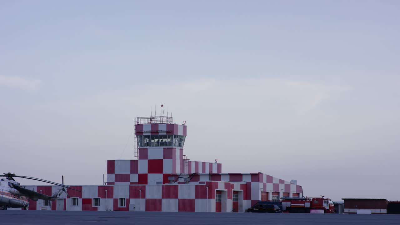 instalación aeroportuaria con torre de control y vehículos de emergencia