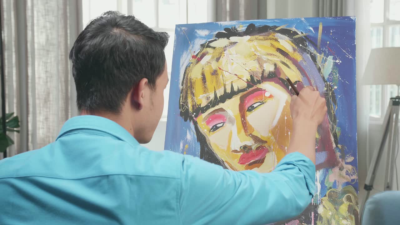 Hind View Of An Asian Artist Man Holding Paintbrush Mixed Colour And Thinking Before Painting A Girl'S Hair On The Canvas