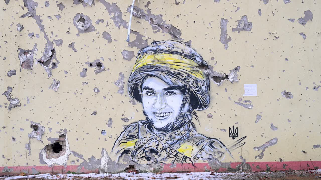 On a war-torn building in Irpin, Ukraine, a mural of a Ukrainian soldier is framed by bullet and shrapnel holes, showcasing the Ukraine-Russia conflict.