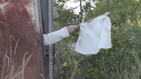 arm waving the white surrender flag on flag pole to signal defeat-1