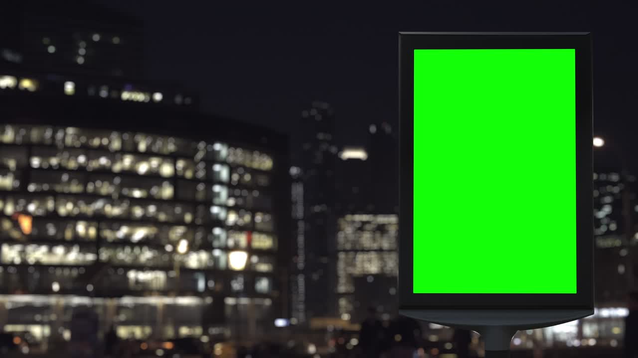 cartelera moderna con una pantalla verde en una calle con tráfico, luces de neón, edificios modernos en el fondo.