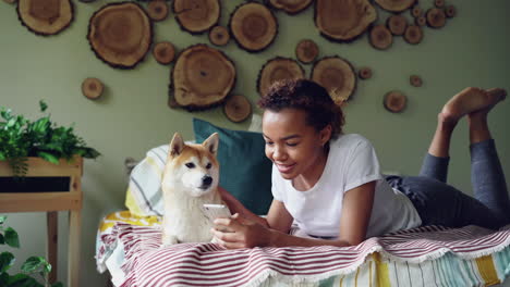 teenager relaxing on bed with dog and phone