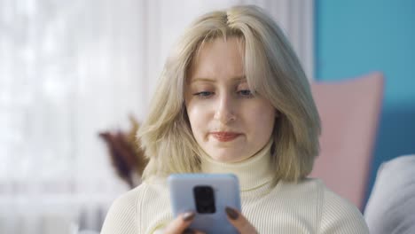 Sad young woman sitting on sofa receives a message with bad news.