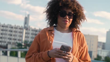 Black-woman-walking-across-the-bridge-and-looking-at-her-mobile-phone.