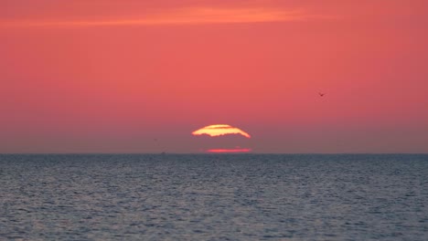 amanecer de primer plano sobre el agua, gran sol rojo naranja