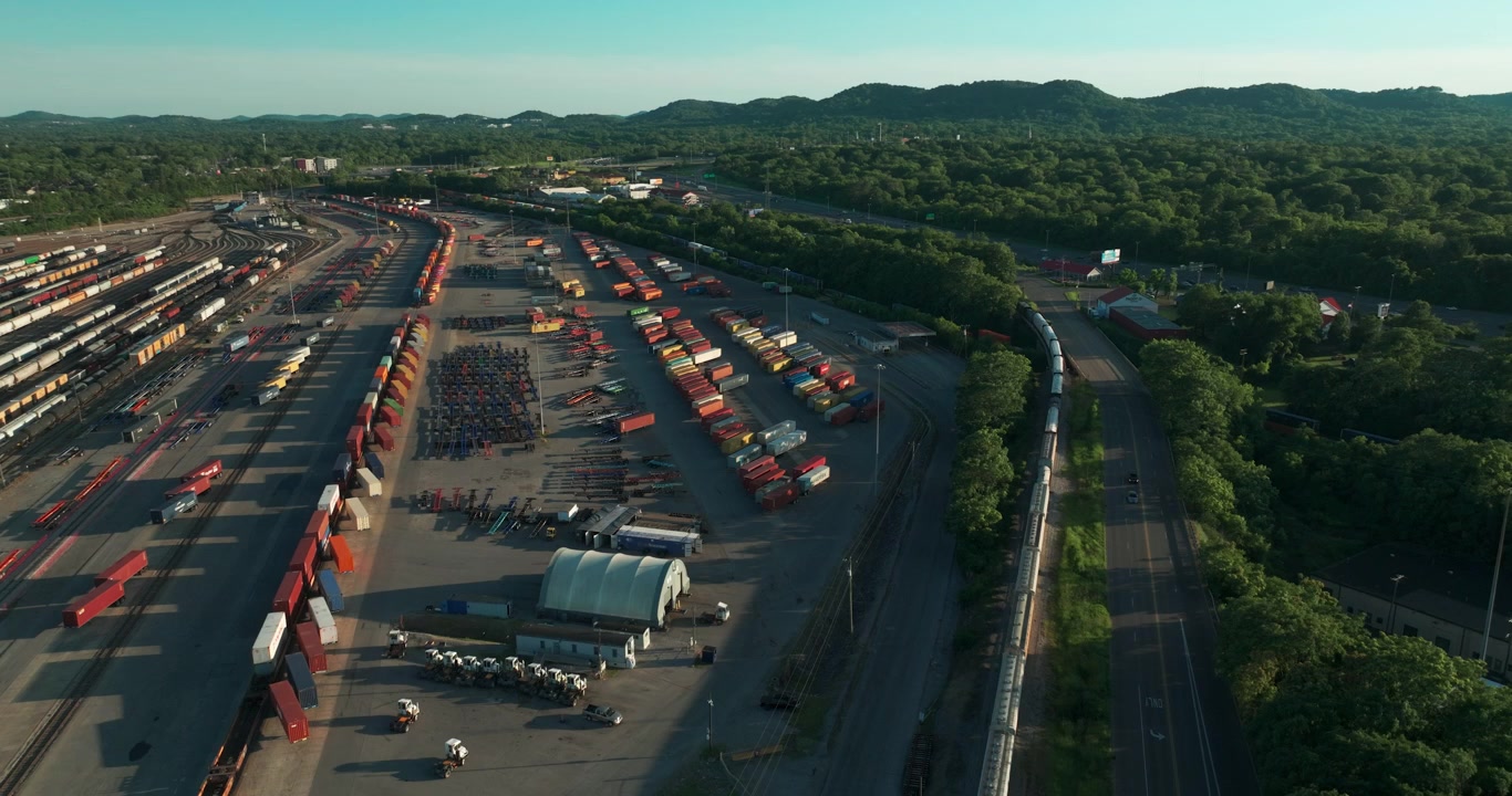 Grande scalo ferroviario intermodale merci con file di container e binari a Nashville, Tennessee, ripresa aerea orbitale al tramonto