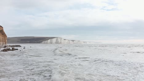 Slow-drone-shot-over-rough-high-tide-towards-seven-sisters-cliffs-South-England