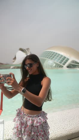 mujer tomando una selfie frente a una fuente y arquitectura moderna