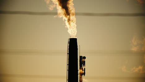 factory chimney pipes emitting air pollution smoke into atmosphere during sunset