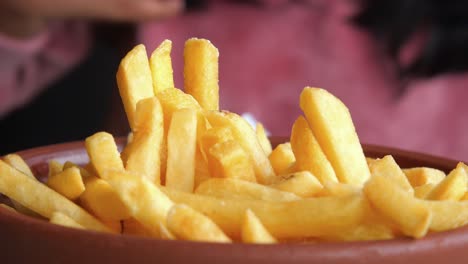 un primer plano de alguien recogiendo papas fritas de un cuenco