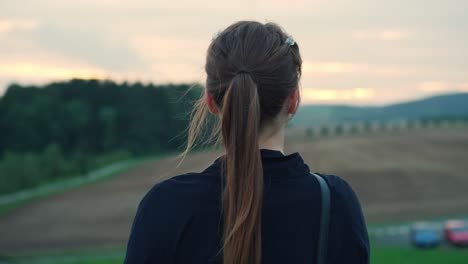 young woman in the countryside stands and looks out contemplating her future