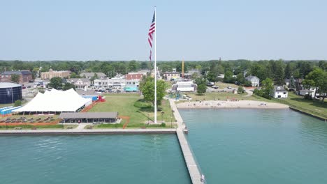 bright and warm lake coast township of new baltimore with usa flag, aerial view