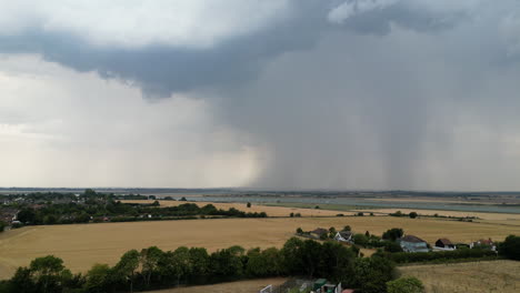 aerial footage of dry summer fields, with large storm cell in the distance with rain being released, drone forward motion