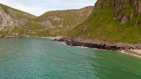 Aerial-shot-of-remote-Lofoten-Sandvika-beach-in-Noway-surrounded-by-steep-cliffs