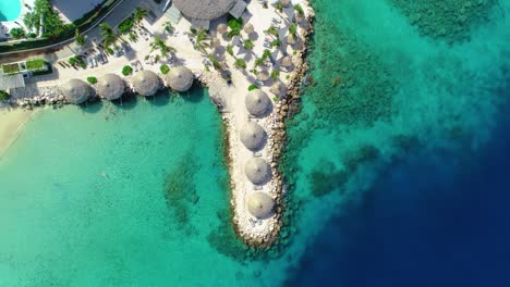 paraguas de hojas de palma de resorts tropicales con vistas al océano azul del caribe, aire hacia abajo