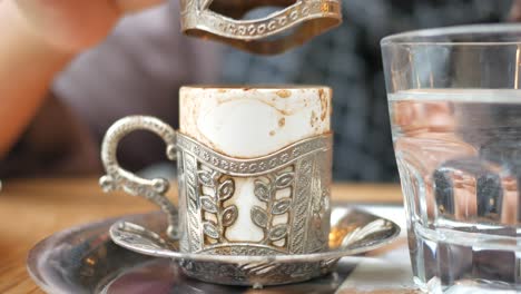 primer plano de una mano sosteniendo una taza de café tradicional turca