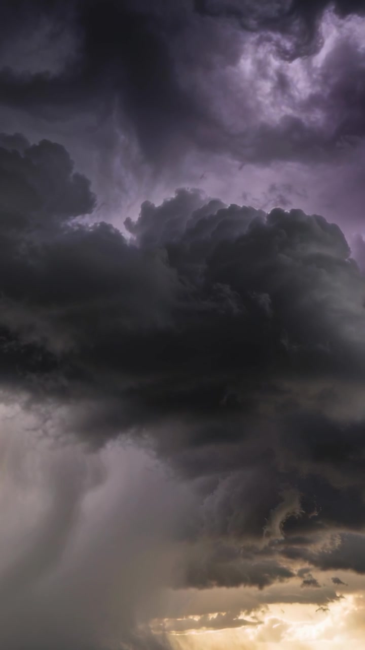 Vertical video: Forming cell growing as flashes pulsing by gold horizon, rain shaft and lilac glow