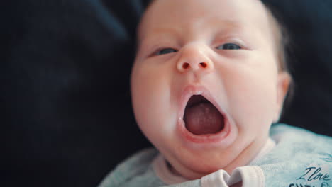 a newborn baby who is rocking and yawning lying on a black background