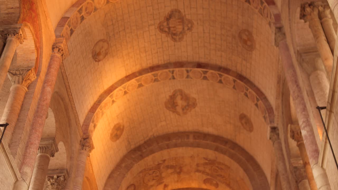 Close up of ceiling inside Basilica of Saint-Sernin in Toulouse, France, showing Romanesque stone patterns and warm illumination