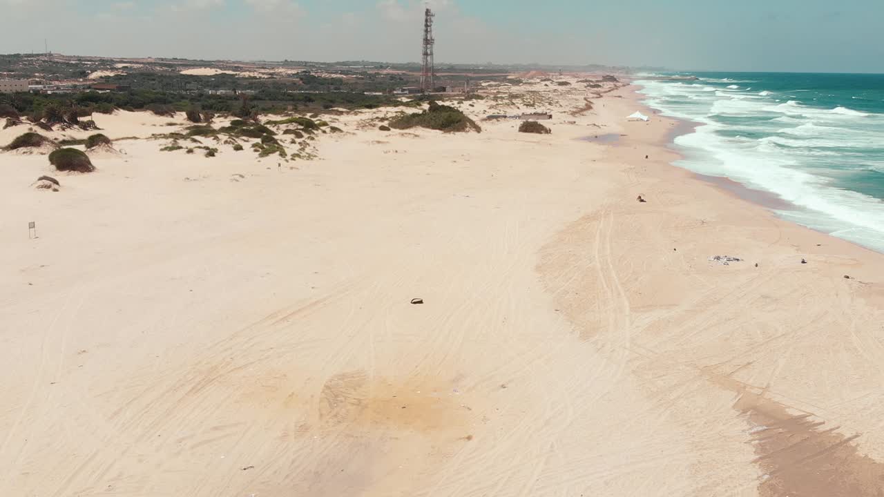 drone aéreo en movimiento que muestra la playa vacía de la costa con antena en el fondo