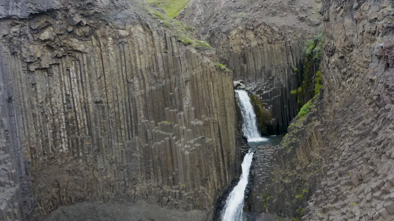 vista aérea de la cascada de litlanesfoss que fluye a través del acantilado con columnas de basalto en el este de islandia
