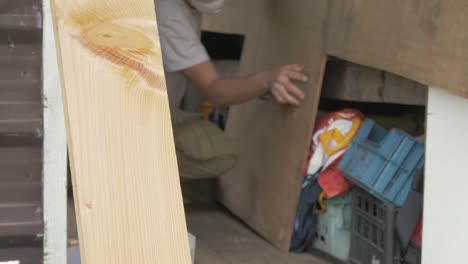 carpenter hand sanding face of plywood sheet