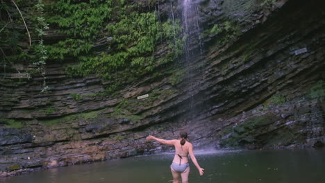 woman swimming in a waterfall pool