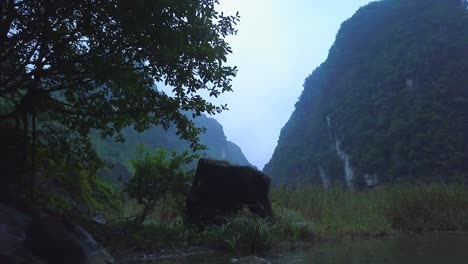 cinematic drone footage of majestic limestone peaks in misty and foggy weather. ricefields in wild jungle in the spring with boat tour canal in tam coc, ninh binh, vietnam