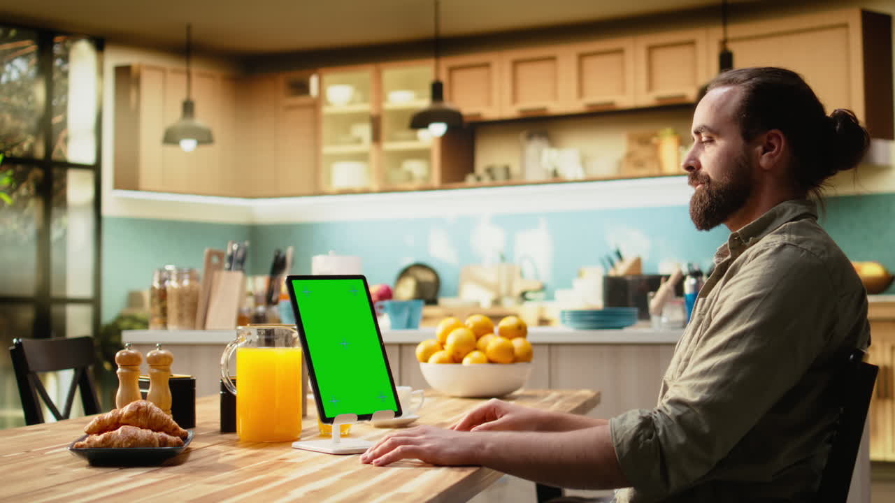 Vertical green screen on tablet with man sitting at wooden table