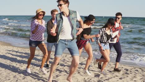 group of young hipster friends running together on a beach at the water's edge. slowmotion shot