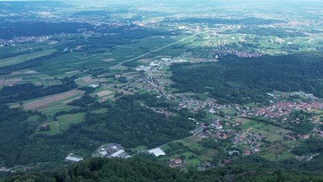 drone panorama of the ivrea morainic amphitheatre seen from brosso, val chiusella, italy, showing lush green plains, woods, and scattered villages under clear sky, high drone shot, slow motion