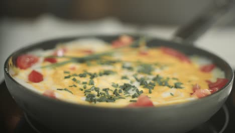 Vegan-scrambled-eggs-with-fresh-tomato-slices-and-fresh-chives-cooking-in-a-pan