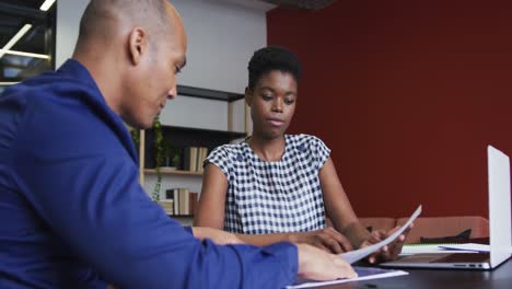 Two-diverse-business-colleagues-sitting-and-discussing-paperwork-in-a-casual-meeting