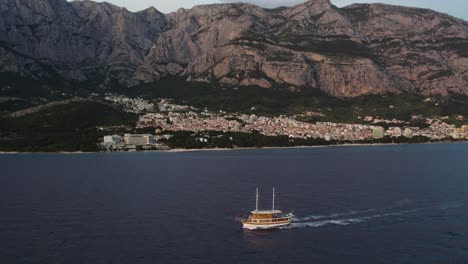 aerial - small tourist cruise ship in adriatic sea near makarska town, croatia