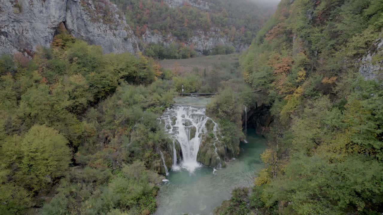 Cascata avvolta nella nebbia che si riversa in un lago limpido, Plitvice, Croazia