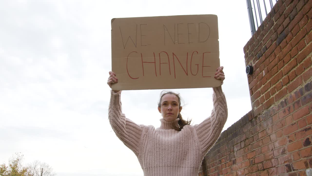 Strong woman walking in protest holding a sign for change on a street low angle