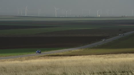 road through fields, with windmills in the distance