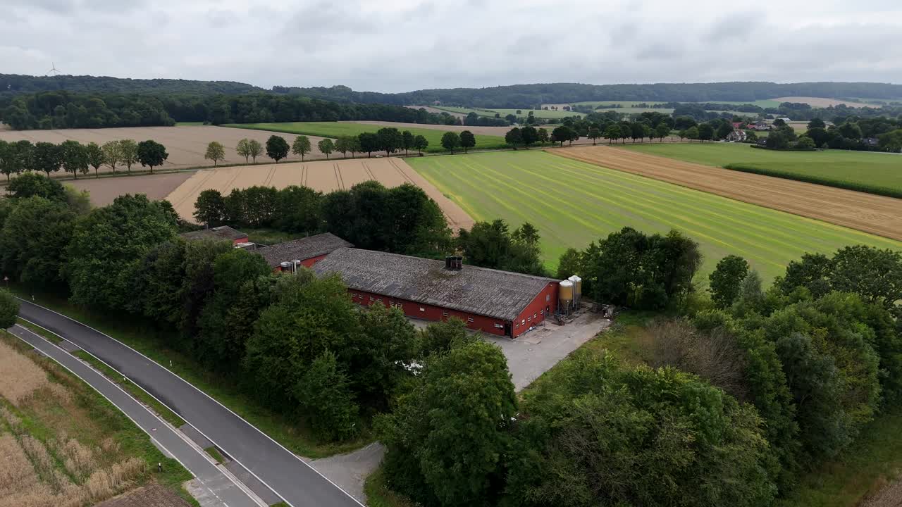 Traditional American farmstead building and barn in rural landscape. Cloudy summer day in Indiana. Aerial lateral wide shot. Rural road with forest trees. Quiet Suburb neighborhoods