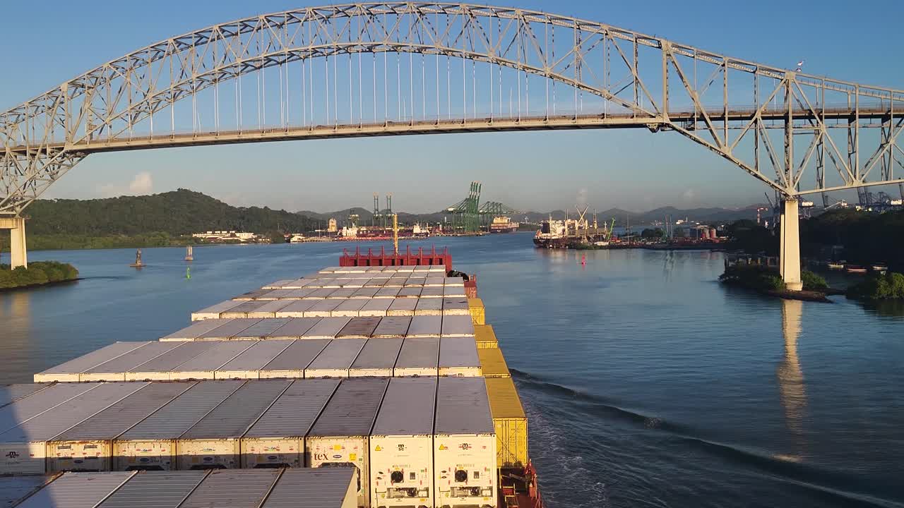 Container ship approaches the Bridge of the Americas on the Panama Canal under clear skies and early sunlight