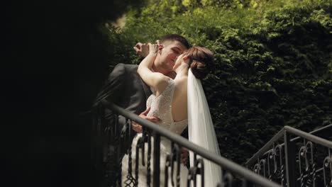 recién casados, novio caucásico con la novia quedarse en las escaleras en el parque, pareja de bodas, hombre y mujer enamorados