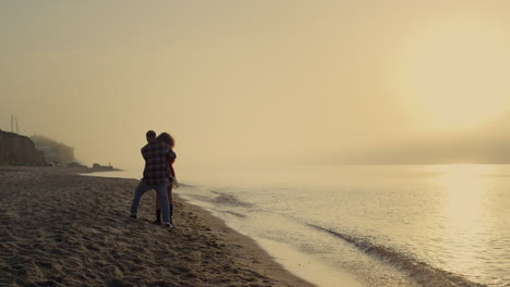 Pareja-Feliz-Divirtiéndose-Juntos.-Un-Hombre-Encantador-Haciendo-Girar-A-Una-Mujer-En-Las-Manos-En-La-Playa.