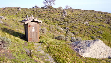 an outhouse on a windy hillside in the old west at steep ravine, california