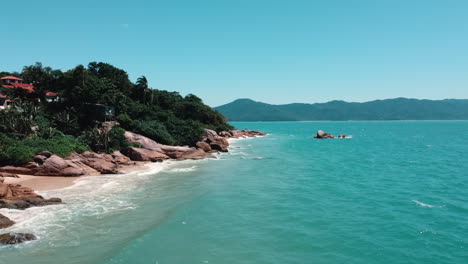 drone-motion-showcasing-the-rocky-formations-and-the-ocean-in-Jurerê-Internacional,-Florianópolis